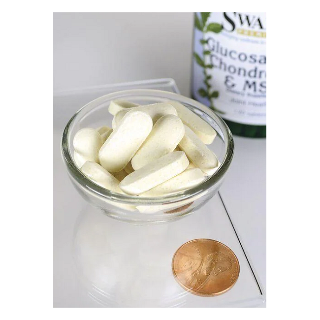 A small glass bowl sits on the countertop with white oblong tablets next to a penny for size comparison. In the background, a partially visible Swanson bottle labeled "Glucosamine, Chondroitin & MSM 120 Tablets" suggests their joint-supportive benefits.