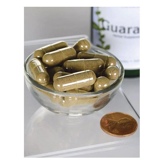 A glass bowl contains Swanson's Full Spectrum Guarana 500 mg capsules, known for their caffeine content, next to a penny.