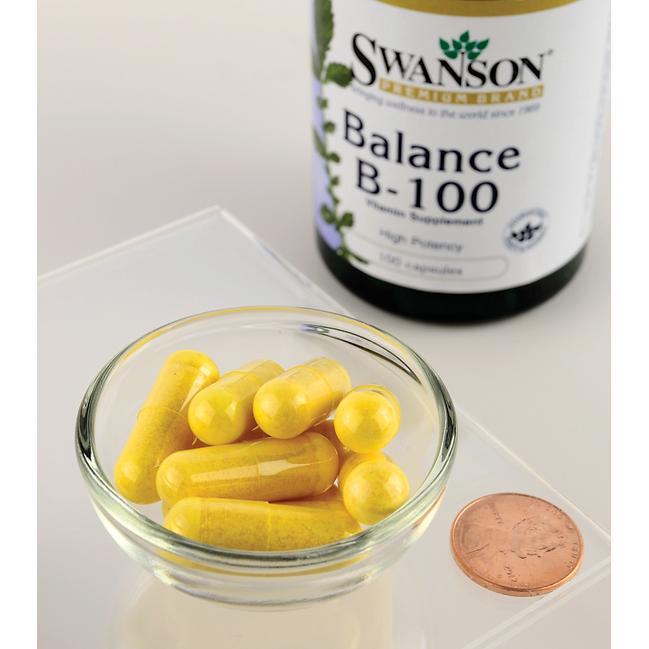 Eine Flasche Swanson Vitamin B-100 Complex - 100 Kapseln, ein Nahrungsergänzungsmittel, das reich an Vitaminen der B-Familie ist, die für den Energiestoffwechsel und die Aufrechterhaltung des Herz-Kreislauf-Systems wichtig sind, mit einem Pfennig daneben.
