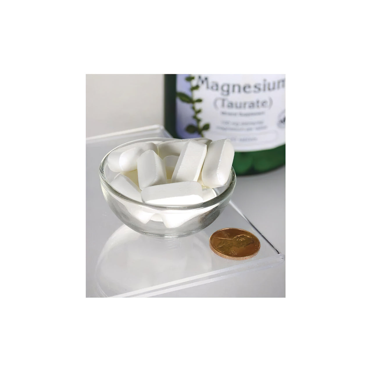 Eine Flasche Swanson Magnesium Taurate 100 mg 120 tab sitzt neben einer Schüssel mit weißen Pillen.