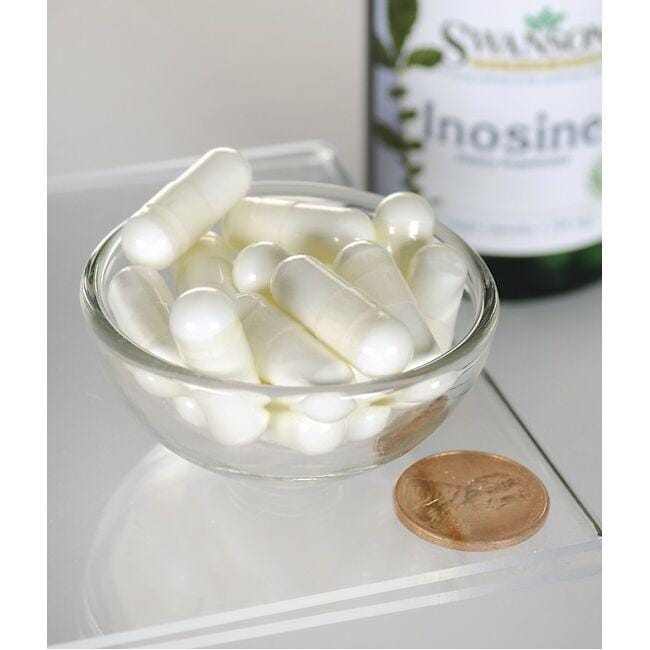 Eine Schale mit weißen Pillen neben einer Flasche Swanson Inosin - 500 mg 60 Veggie-Kapseln.