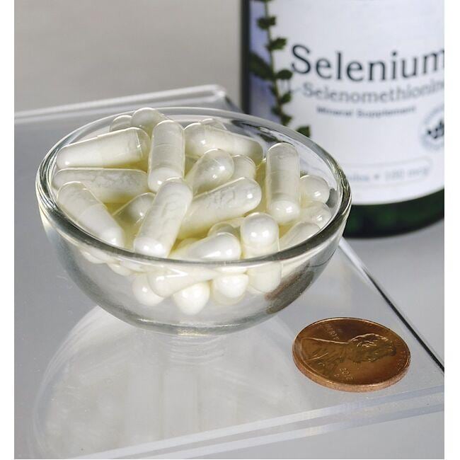 Swanson Selen - 100 mcg 200 Kapseln L-Selenomethionin in einer Schale neben einem Penny, bietet antioxidative Unterstützung für die kardiovaskuläre Gesundheit.