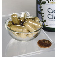 Daumennagel für Cats Claw - 500 mg 100 Kapseln in einer Schale neben einer Flasche Swanson.
