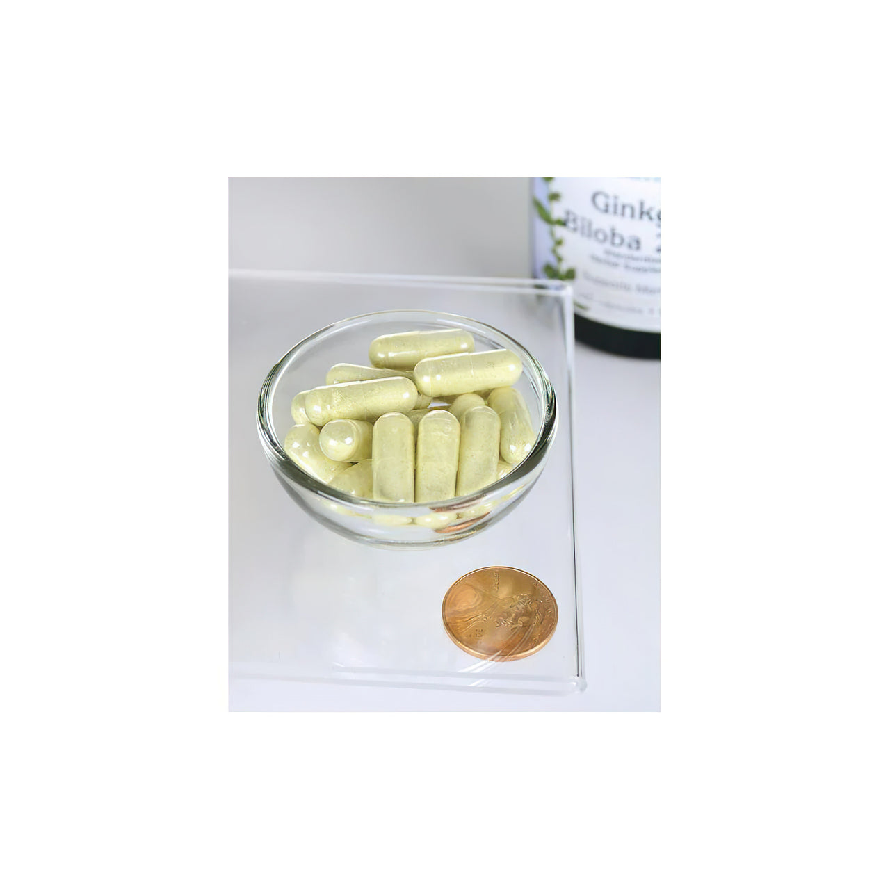 Eine Schale mit Swanson Ginkgo Biloba Extract 24% 60 mg 240 cap mit einer Münze daneben.
