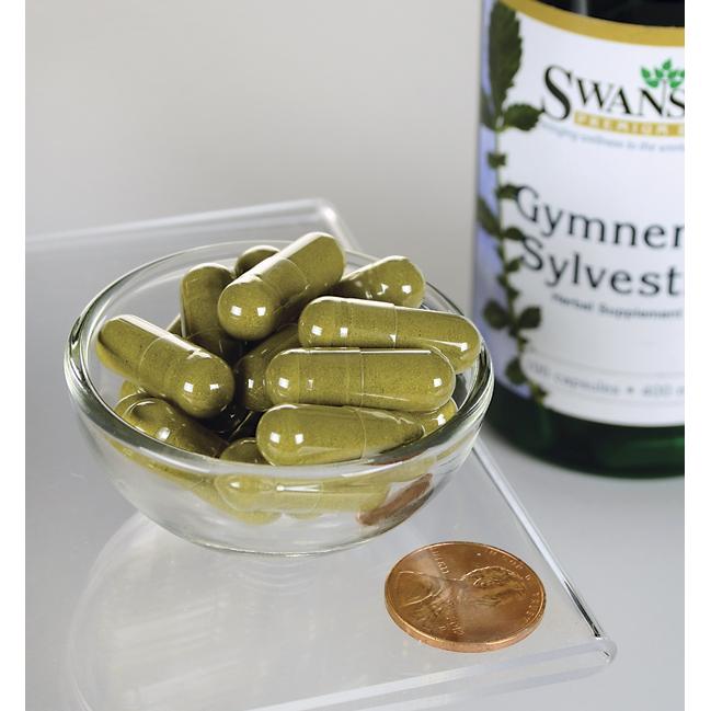 Eine Flasche Swanson Gymnema Sylvestre Leaf - 400 mg 100 Kapseln mit einem Pfennig in einer Schale.