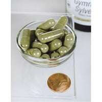Vorschaubild für Eine Schale Swanson Gymnema Sylvestre Extract - 300 mg 120 Kapseln neben einer Münze.